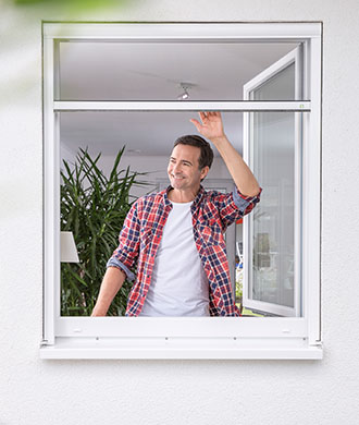Mann an einem offenen Fenster mit Fliegengitter von Systec 